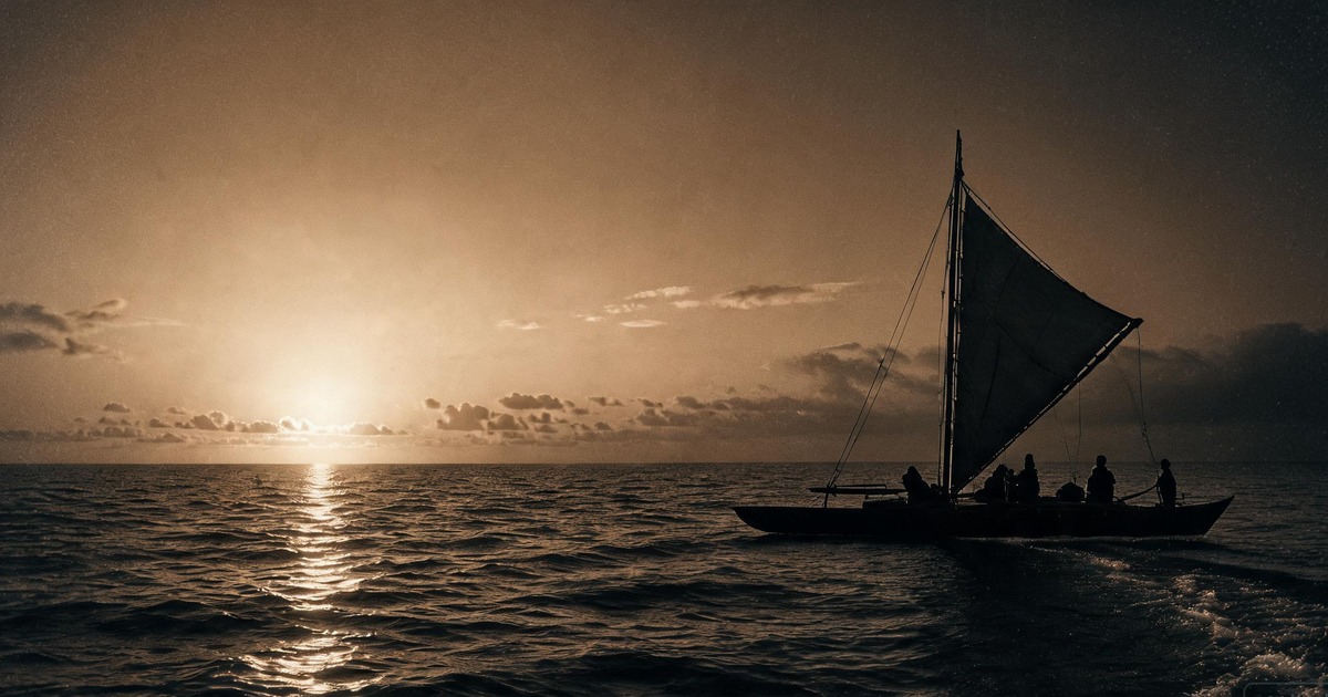 A voyaging canoe under sail on open ocean at dawn
